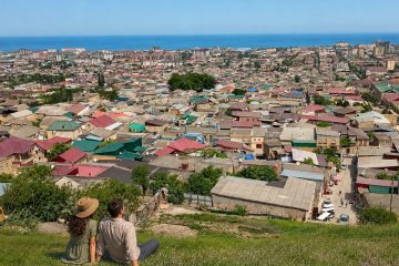 Панорама Дербента и Каспийского моря, туристическая пара смотрит на город