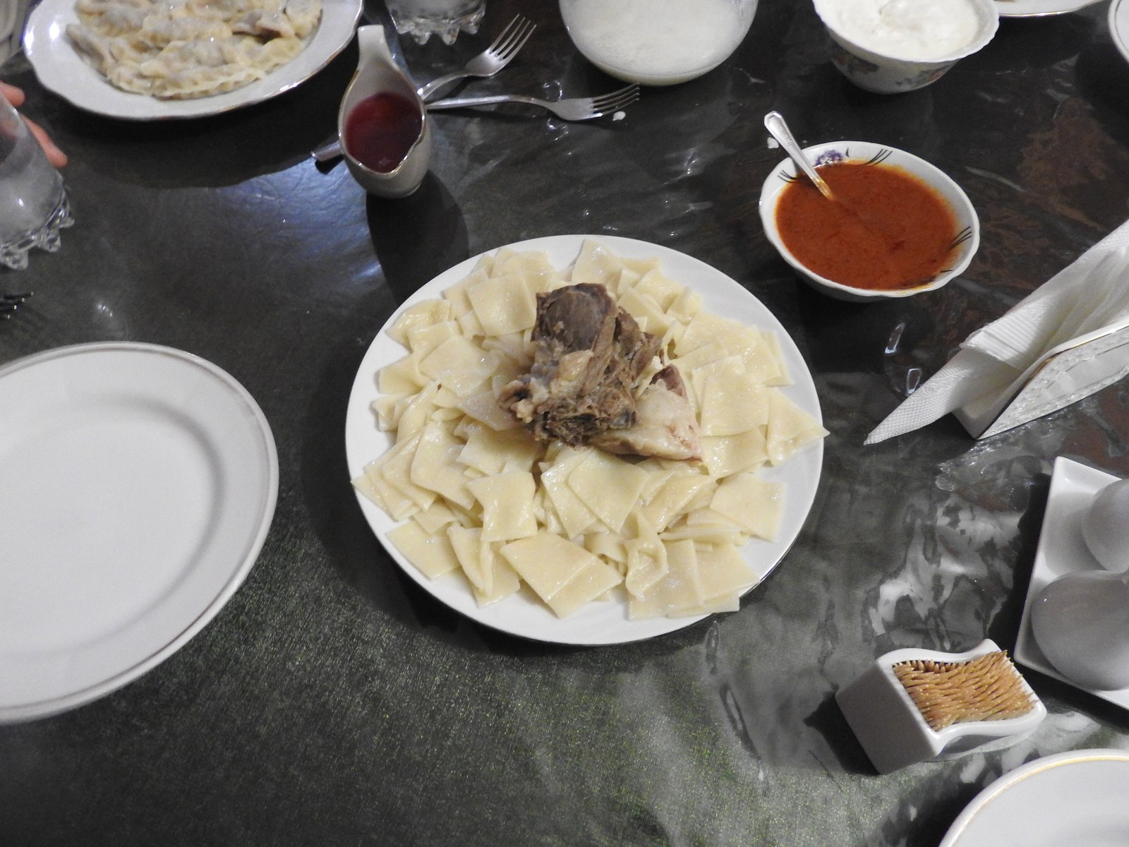 Хинкал из тонких квадратов теста с мясом и соусами на столе в Дербенте