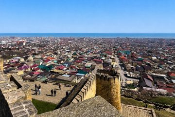 Панорама Дербента и Каспийского моря с посетителями на террасе крепости