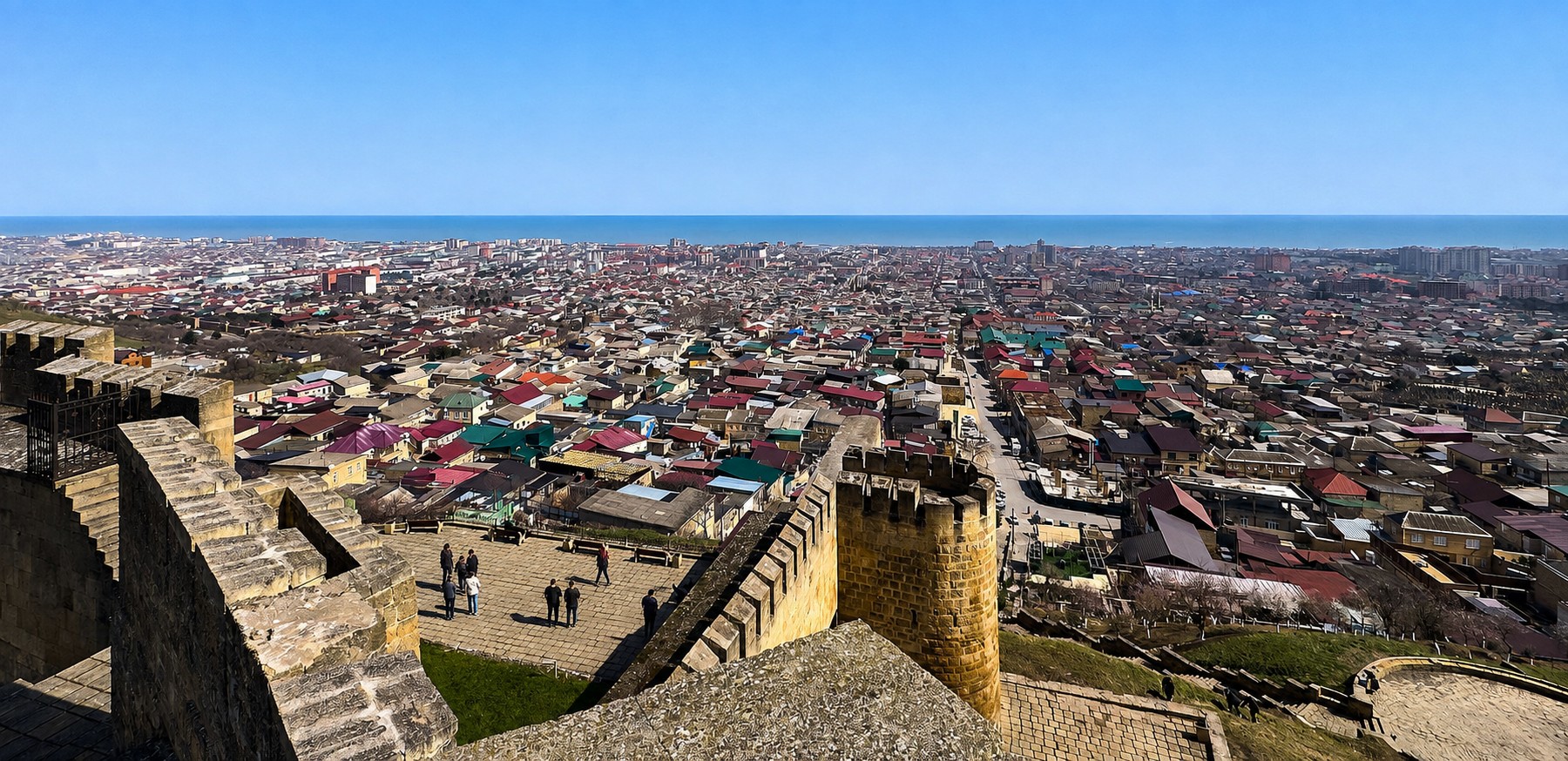 Панорама Дербента и Каспийского моря с посетителями на террасе крепости