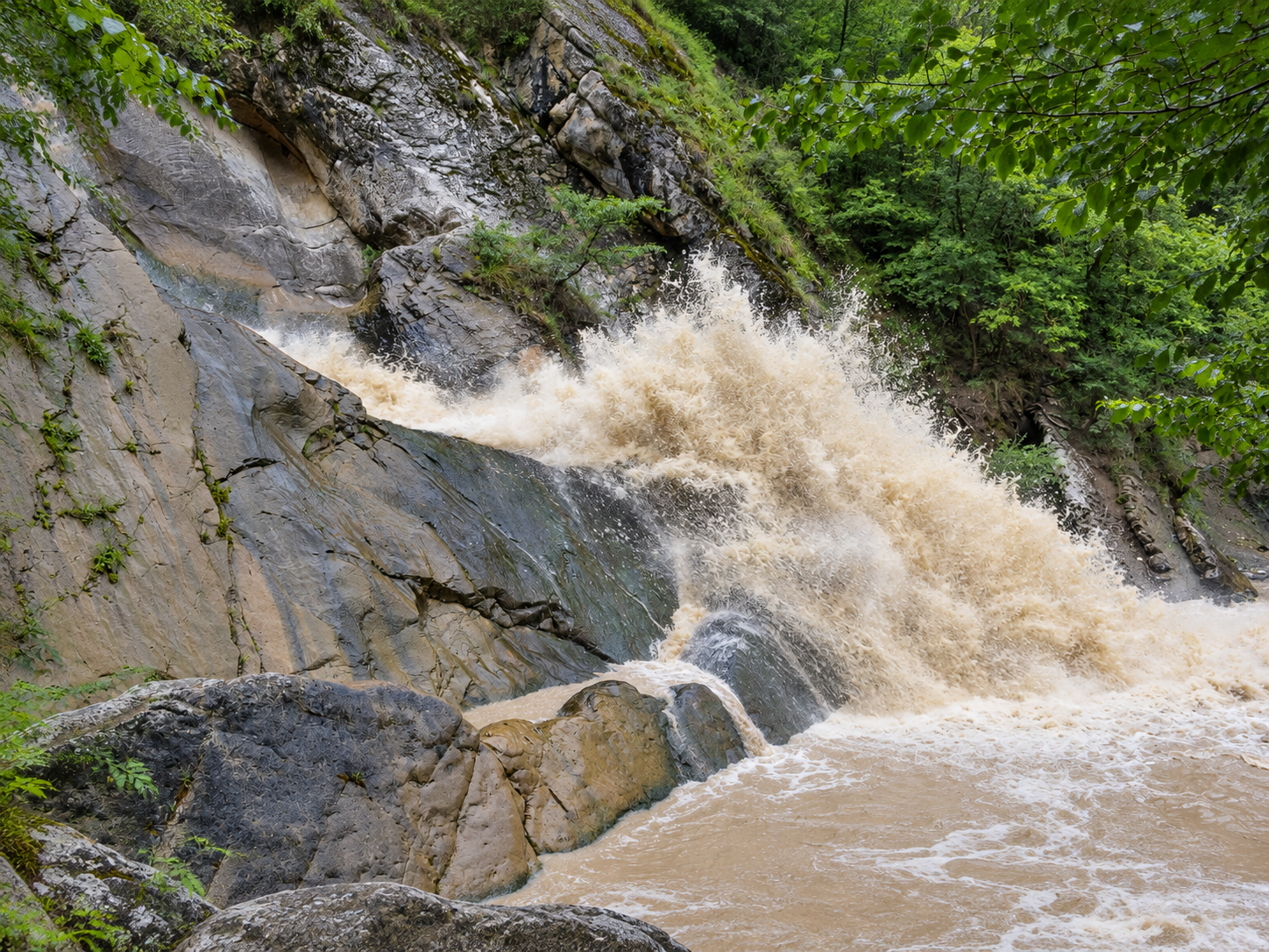 Бурная вода и мокрые камни у Ханагского водопада.